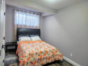 - une chambre avec un lit doté d'un couvre-lit orange et d'une fenêtre dans l'établissement Cozy Basement Suite - private entrance - Free Netflix, à Edmonton