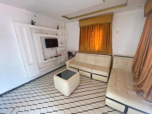 sala de estar con 2 sofás y TV en Biji Paradise Hotel en Benin City