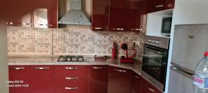 La cuisine est équipée de placards rouges et d'un four avec plaques de cuisson. dans l'établissement duplex avec jardin, à Dar el Haj Ahmed Souid