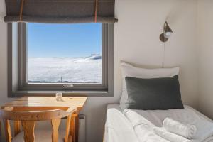 a bedroom with a bed and a table and a window at Halne Fjellstugu in Maurset