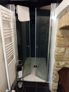 a glass shower in a bathroom with a chair at La taverna sotto la torre in Massa Marittima