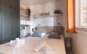 um quarto com uma grande cama branca e 2 almofadas em ISOLA VERDE Camping Village em Nettuno