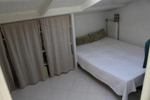um pequeno quarto com uma cama e uma janela em Petite villa dans copropriété avec piscine et vue mer. em Hyères