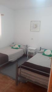 a bedroom with two beds and a white wall at costa del silencio in Costa Del Silencio