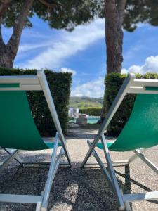 duas cadeiras verdes e brancas sentadas ao lado de uma piscina em Aviotel Residence em Marina di Campo
