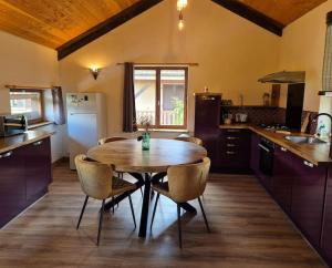 een keuken met een houten tafel en stoelen bij Les Vergers d'Epona "Fremifontaine VOSGES" in Frémifontaine +24 foto's