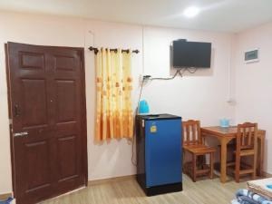 Habitación con nevera, puerta y mesa. en OYO 75488 Leelawadee View Resort (Amnatcharoen) en Amnat Charoen