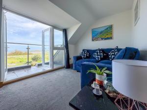 a living room with a blue couch and a large window at Waves Guest Suites in Castel