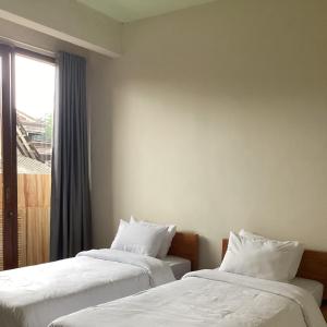 dwa łóżka w pokoju z oknem w obiekcie L'JAVAS VILLAS w mieście Kalibendo
