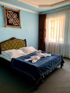 Un dormitorio azul con una cama con sábanas azules y una ventana en Guest House Emily en Bokonbayevo