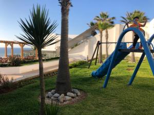 une aire de jeux avec toboggan et palmier dans l'établissement Luxery stay with seaview, pool, green space & Sunset orientation near Rabat, à Sidi Bouqnadel