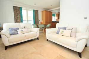 a living room with two white chairs and a table at 50m FROM THE BEACH, dogs welcome in St Merryn