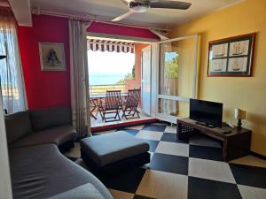 a living room with a couch and a television and a balcony at Appartamento Vista Mare - Spriano in Rio Marina