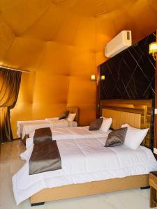 two large beds in a room with an orange wall at Eileen luxury camp in Wadi Rum