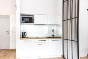 a white kitchen with white cabinets and a microwave at Europejski Boutique Hotel in Radom