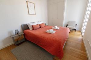 een slaapkamer met een bed met oranje lakens en een stoel bij Casas do Forte Sun 4pax by Portugal Hideaway in Cabanas de Tavira +30 foto's