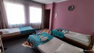 2 Betten in einem Zimmer mit rosa Wänden in der Unterkunft Guest House Emily in Bokonbayevo