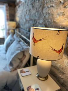 a table with a lamp with a red bird on it at The George and Dragon Inn in Knighton