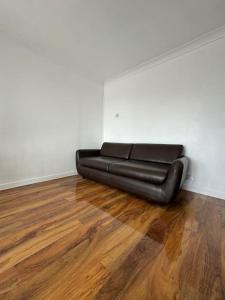 Eine schwarze Couch in einem leeren Raum mit Holzboden in der Unterkunft Flat on high street in Saltdean