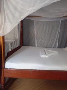 a bed with a canopy with a white mattress at Ikulu house in Mapenya