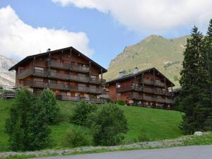 two buildings on a hill with mountains in the background at Appartement Le Grand-Bornand, 2 pièces, 5 personnes - FR-1-241-164 in Le Grand-Bornand