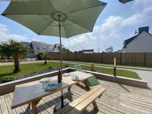 una mesa de picnic con una sombrilla verde en la cubierta en Maison lumineuse près de la plage - Jardin privé, 3 chambres, équipements bébé inclus - FR-1-542-57, en Trégastel