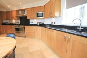 a kitchen with wooden cabinets and a sink and a table at STYLISH, BEACHSIDE apartment, sea views in St Merryn