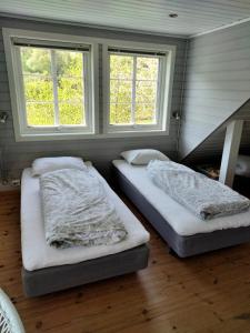 duas camas num quarto com duas janelas em Anneks i naturskjønne Gitlevåg em Lyngdal