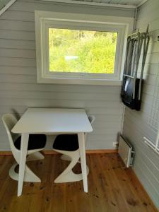 Una pequeña mesa blanca en una habitación con ventana en Anneks i naturskjønne Gitlevåg, en Lyngdal