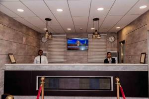 two men standing at a counter in a lobby at Fabino by Top Rank Hotels in Abuja