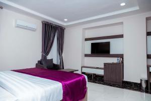 a hotel room with a bed and a tv at Fabino by Top Rank Hotels in Abuja