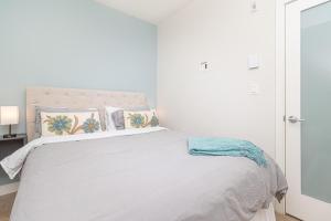 a white bedroom with a large bed with pillows at Sunlit Urban Charm In Old Town Victoria in Victoria