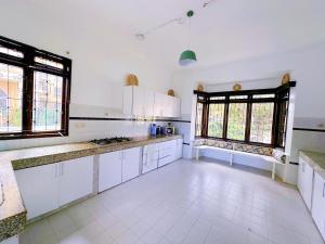 a large kitchen with white cabinets and windows at Villa Ella in Mombasa +11 photos