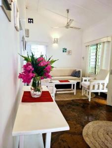una sala de estar con un jarrón de flores rosas sobre una mesa en 2 Bedroom Holiday Cottages Bofa Road, Kilifi, en Kilifi