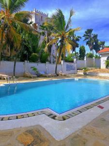 a large swimming pool with palm trees and a building at Villa Ella in Mombasa