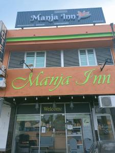 un magasin avec un panneau sur le côté d'un bâtiment dans l'établissement Manja Inn, Paka, à Paka