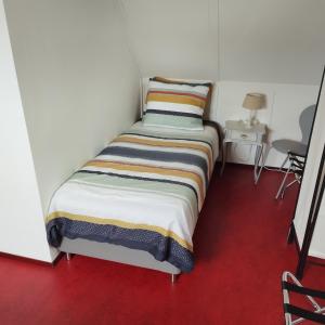 Habitación pequeña con 2 camas individuales y suelo rojo. en La Nostra casa en Alblasserdam