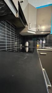 een keuken met een zwart aanrecht en witte kasten bij Olympique 700m du Stade de France in Saint-Denis