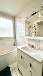 een witte badkamer met een wastafel, een bad en een spiegel bij Olympique 700m du Stade de France in Saint-Denis