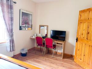 a room with a desk with two chairs and a television at Kilcar Lodge in Kilcar