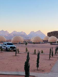 a white suv parked in a desert with domes at Eileen luxury camp in Wadi Rum