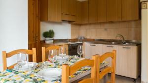 uma cozinha com uma mesa e cadeiras com copos de vinho em Casa Ficus em Porto Ottiolu