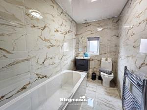 曼徹斯特的住宿－Modern & Spacious 5-bedroom House With Game Room，带浴缸和卫生间的浴室。