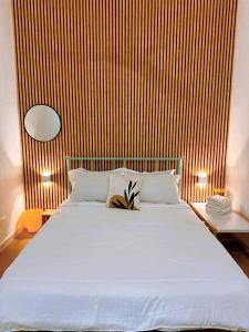 a bedroom with a white bed with a wooden wall at Muji Homestay Ria Heights Tawau in Tawau