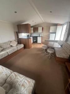 Beautiful two bedroom caravan, Eastchurch في Eastchurch: غرفة معيشة مع أريكة وطاولة