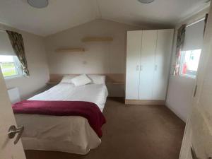 Beautiful two bedroom caravan, Eastchurch في Eastchurch: غرفة نوم بسرير كبير ودواليب بيضاء