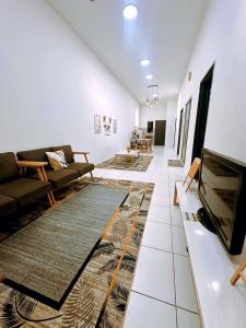 a living room with couches and a flat screen tv at Muji Homestay Ria Heights Tawau in Tawau
