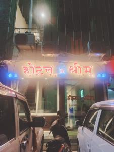 een bord aan de zijkant van een gebouw 's nachts bij Hotel Shreem in Ujjain