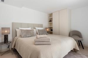 a white bedroom with a large bed and a chair at 20600 - Luxurious Beachside Villa Near Marbella in Marbella