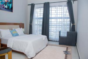 a bedroom with a white bed and a large window at Ladari Apartments in Babati